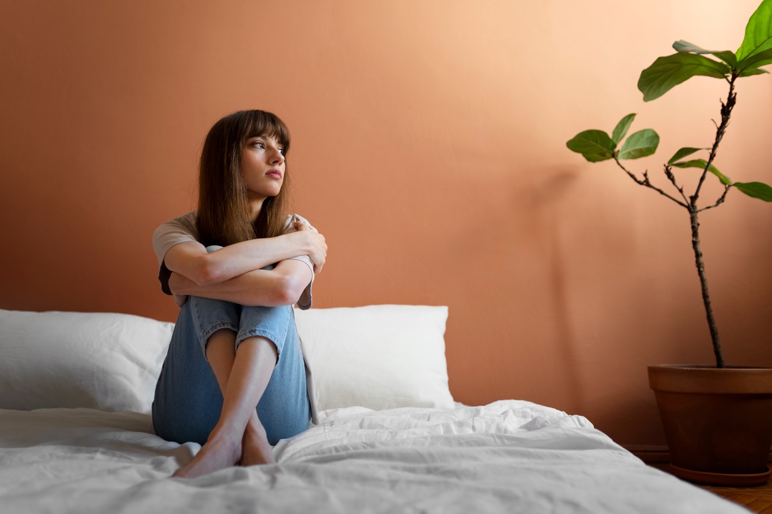 Mulher pensativa sentada na cama