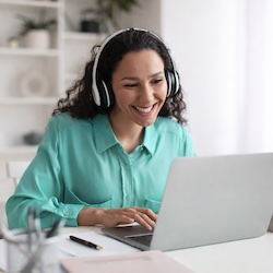 A pessoa usa fones de ouvido no laptop